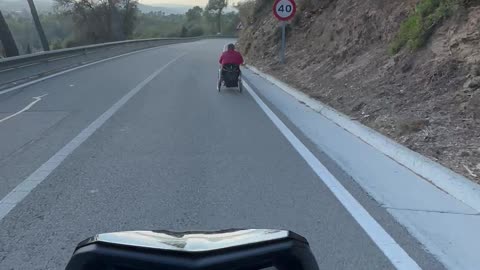 Motorcycle Follows Wheelchair Down Hill