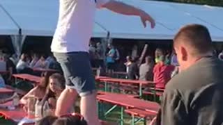 Guy on picinic table falls from one table to another red tables