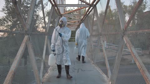 people with masks sanitizing-a-pedestrian-bridge