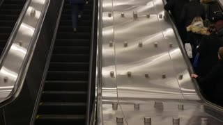 Guy blue jacket running up escalator