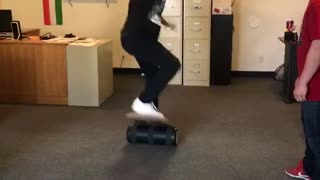 Black hat guy on balance board in office falls on shoulder