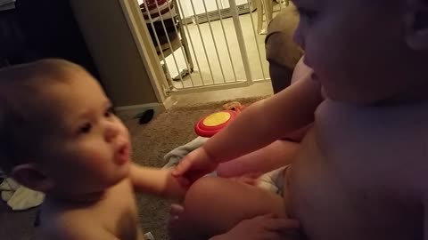 Baby tries to pick up twin brother