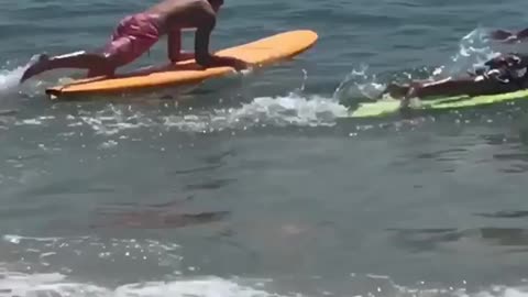 Guy orange surfboard rides wave into guy on green surfboard