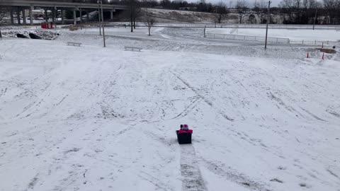 Little girl sledding in a plastic tub.