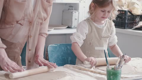 A Mother And Daughter Flattening Dough With Rolling Pins