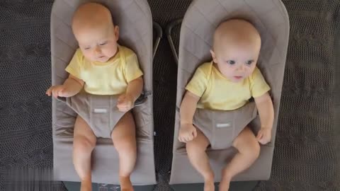 Two Adorable Twin Babies Smiling And Swinging On Bouncers