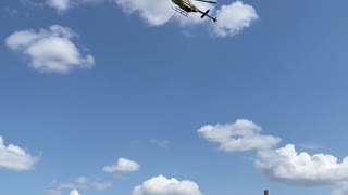 Helicopter crop dusting pops over trees and turns
