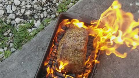 Cooking beef roast on pan off of grill on floor