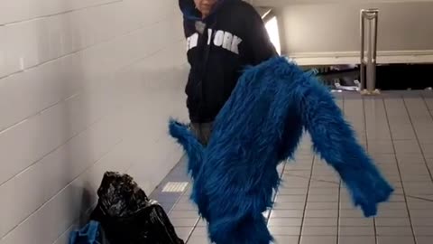 Woman putting on furry blue costume onesie