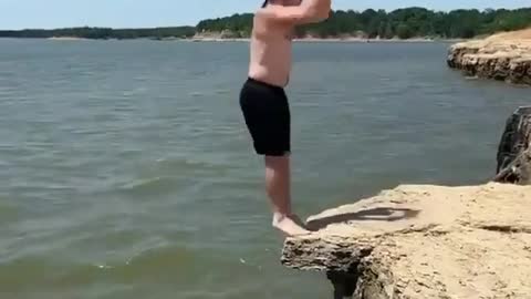 A man jumps off a cliff, which ends up cracking and he falls into the river
