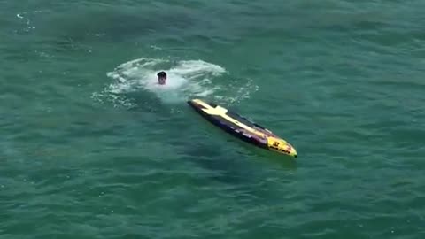 Guy yellow surfboard paddle white shirt falls into water ocean