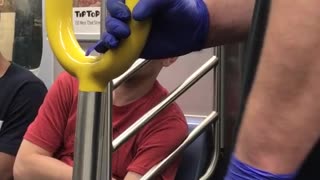 Person on subway with purple gloves holding onto pole