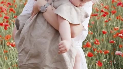 Woman Carrying Her Baby While Standing on Red Poppy Flower Field