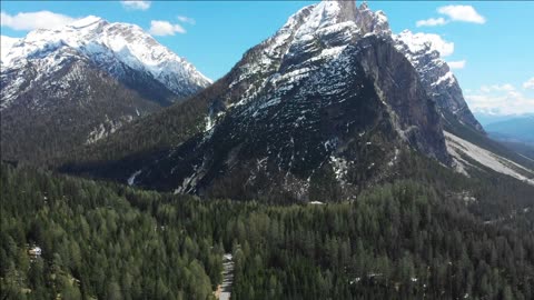 a landscape of mountains with snowy summits and forest dolomiti italy