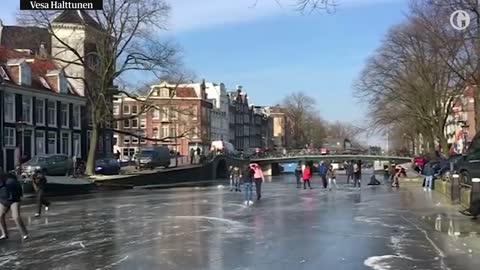 Ice skaters glide over frozen canal in Amsterdam