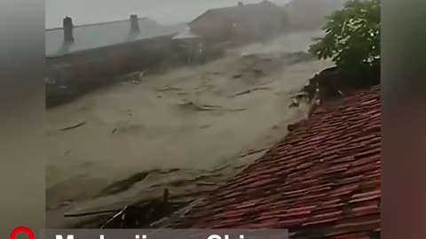A scary scene of surging flood water rushing into the village filmed by a villager from a rooftop