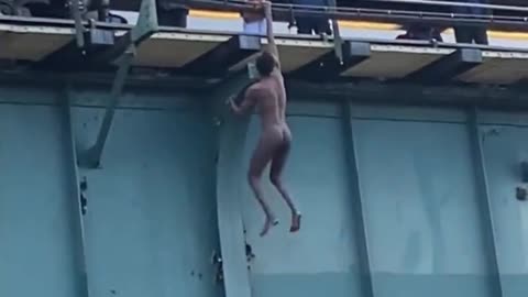 INSANE video shows naked man dangling by one arm from a 6 train station in the Bronx.