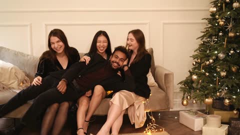 A young man celebrates with pretty girls and falls on their lap