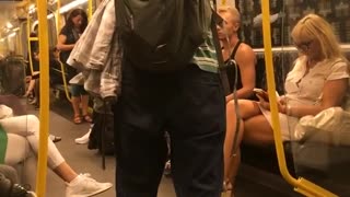 Man in green striped shirt playing flute on subway