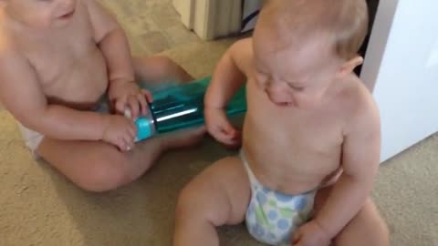 Adorable twins argue over water bottle