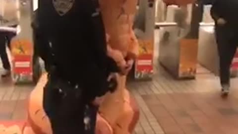 Nypd officers put handcuffs on guy in an orange inflatable t rex dinosaur suit and take a picture