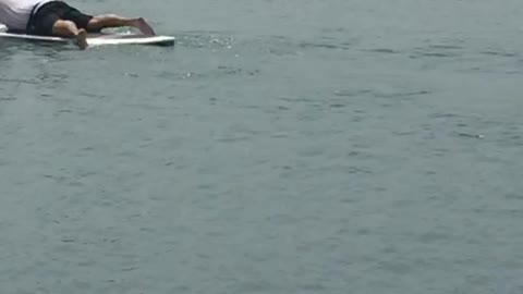 Two guys in the water laying down and paddling