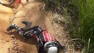 Guy tries to ride his dirt bike down hill slowly but falls down instead