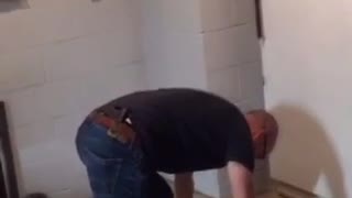 Bald guy black shirt in basement tries to do handstand fails and hits wall