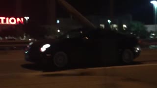 Black car with surfboard coming out of moonroof