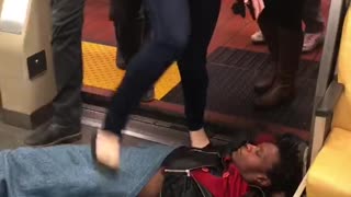 Guy laying on subway floor people walking over him