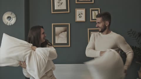 The couple having fun with pillows quarreling