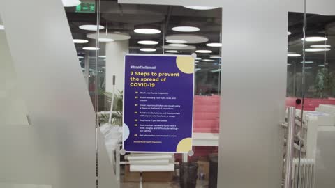 A Man Posting a Covid-19 Awareness Poster on a Glass Wall