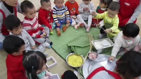 Vietnamese traditional game - Instructing children how to make Chung cake.