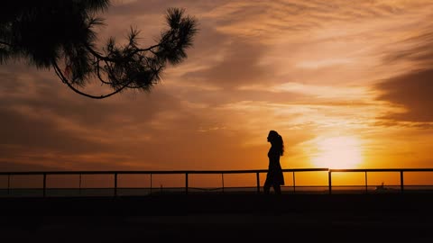 Backlit woman walking at sunset