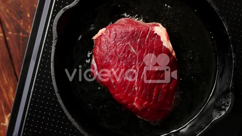 Big piece of meat on pan-From above view of fresh raw meat laid on black pan in process of cooking i