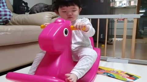 Baby sleeping on a toy horse.