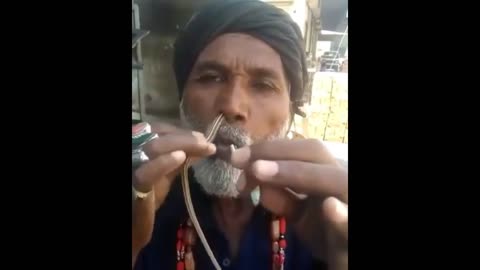 An old man pushes the snake through his nose and out of his mouth