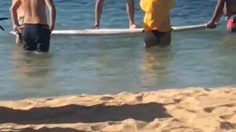 Man in red shorts stands on surf board in ocean