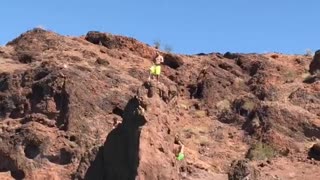 Guy green shorts jumping off cliff into water