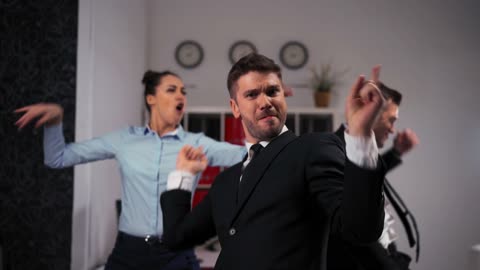 Three joyful collegues in formal suits dancing cheerfully in office.