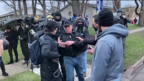 Protesters throw a water bottle at a CNN crew membe