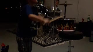 Little kid boy hitting playing fire drums knocks it over