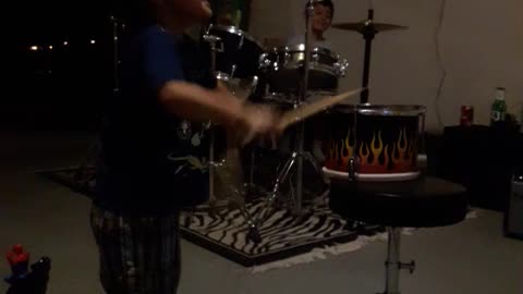 Little kid boy hitting playing fire drums knocks it over