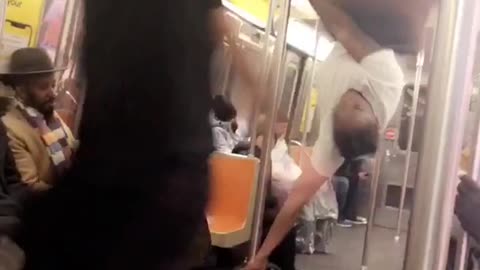 Performer on subway train uses pole to walk and spin around on the roof, "pyt" dance