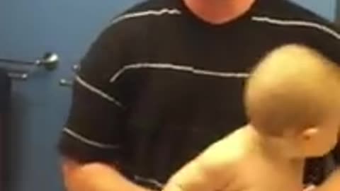 Baby adorably flexes muscles with dad