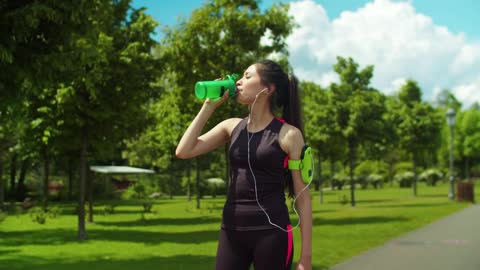 Woman in activewear drinking water after running