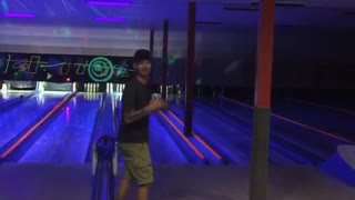 Guy black shirt tossing item at bowling pins