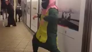 Man green dinosaur outfit dancing pink mask