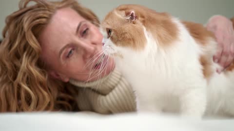 A Woman Petting Her Cat On Bed