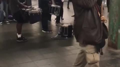 Old man with cane dances to drummers in subway